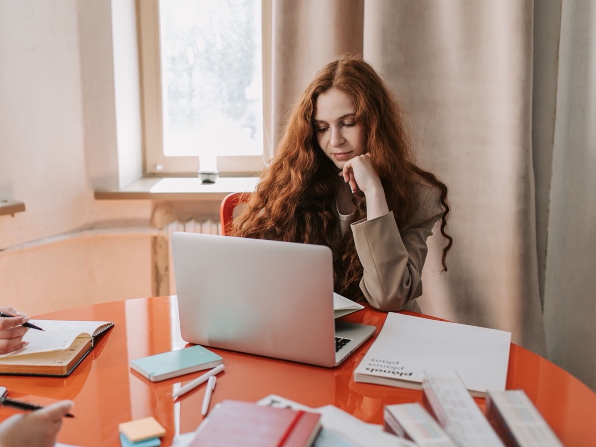 A woman working at a laptop at a shared table with colleagues