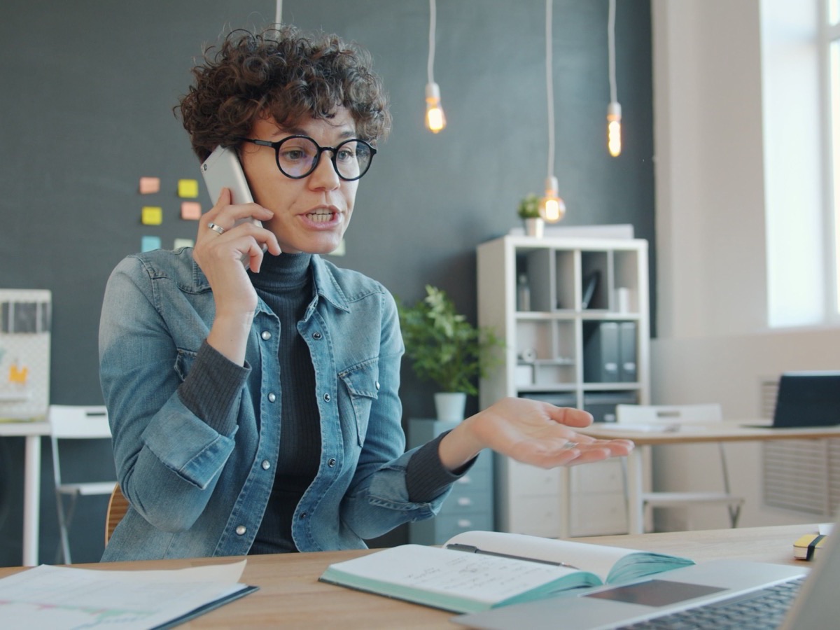 A woman on the phone at her desk in an open-plan office
